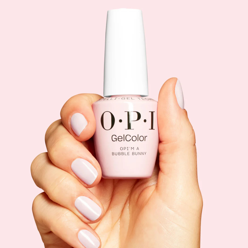 Hand holding a bottle of OPI GelColor nail polish with matching nails on a pink background